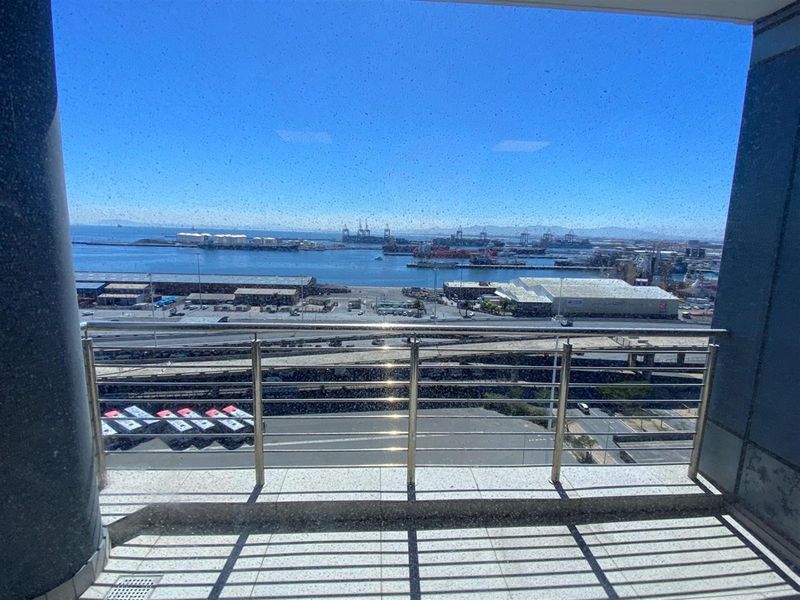 A balcony with a stainless steel railing offering an expansive view of the harbor and industrial port area.