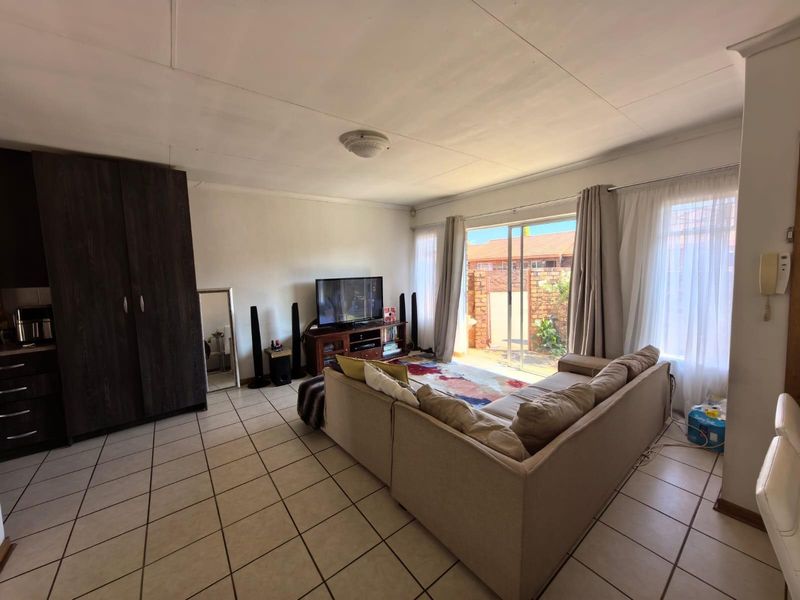 Open plan living area featuring tiled flooring, built-in cabinetry, and sliding glass doors providing direct access to the rear patio and garden.