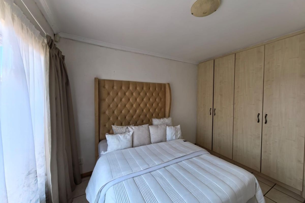A bedroom featuring built-in wooden cabinetry and tiled flooring, offering a functional space with natural light from the adjacent window.