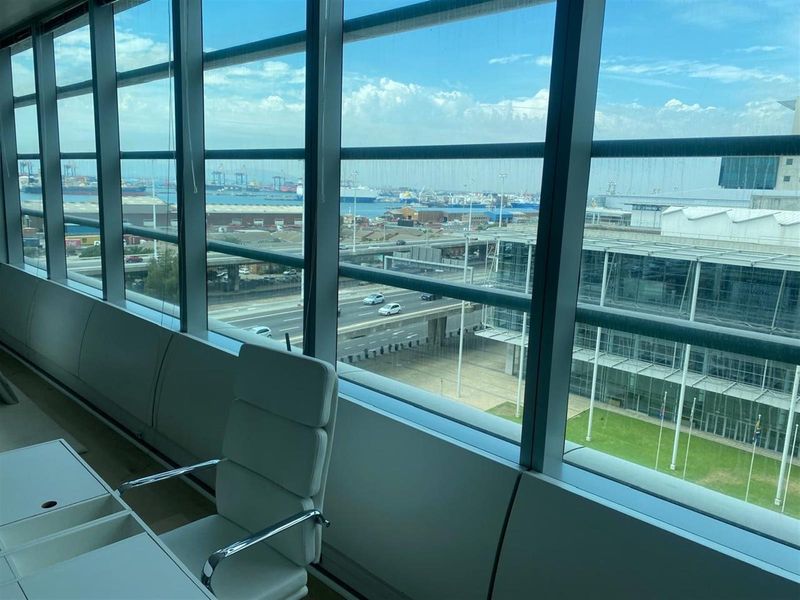 Modern office space featuring expansive floor-to-ceiling windows with panoramic views of the harbor and city infrastructure.