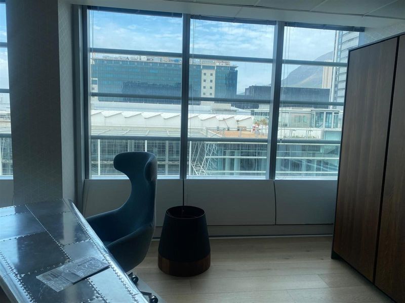 A modern office space featuring large floor-to-ceiling windows that provide ample natural light and an urban city view.