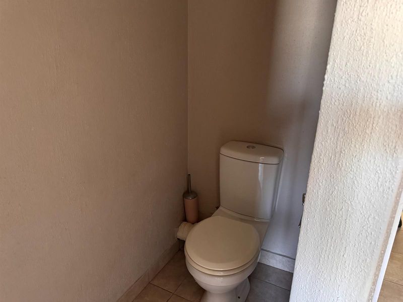 A compact guest toilet featuring a standard white ceramic toilet suite and neutral tiled flooring.