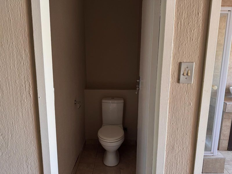 A small, functional guest toilet room featuring a standard white toilet and neutral wall finishes.