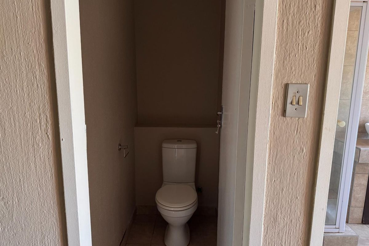 A small, functional guest toilet room featuring a standard white toilet and neutral wall finishes.