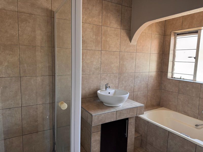 A functional bathroom featuring a built-in bathtub, a separate shower enclosure, and a tiled vanity with a vessel sink.