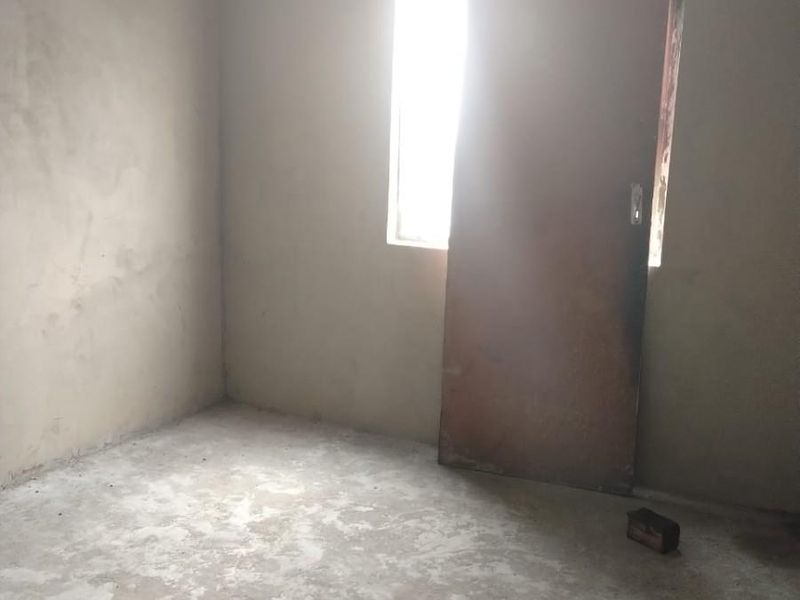 An unfinished bedroom space featuring raw plastered walls and a concrete floor, offering a blank canvas for renovation and custom interior design.