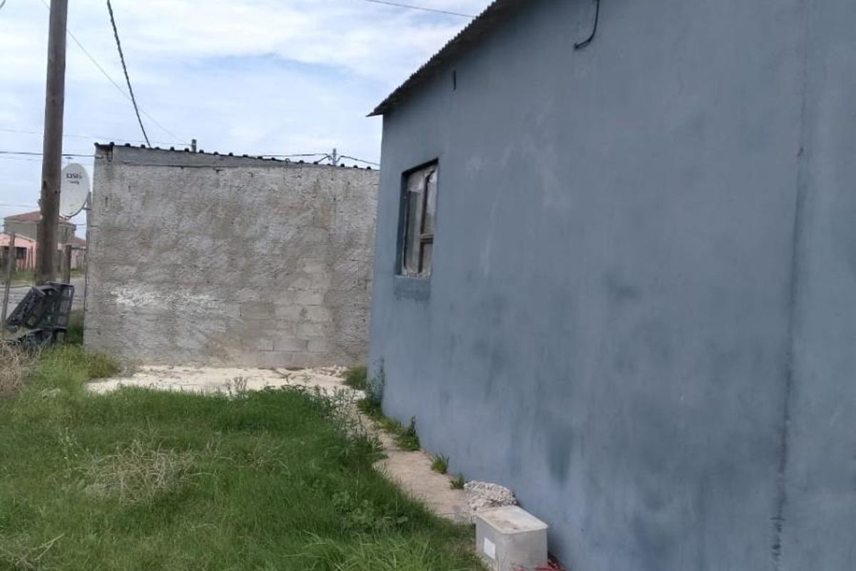 Rear view of the property showing the exterior wall, corrugated metal roofing, and television antenna installation.