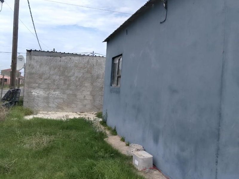 Rear view of the property showing the exterior wall, corrugated metal roofing, and television antenna installation.
