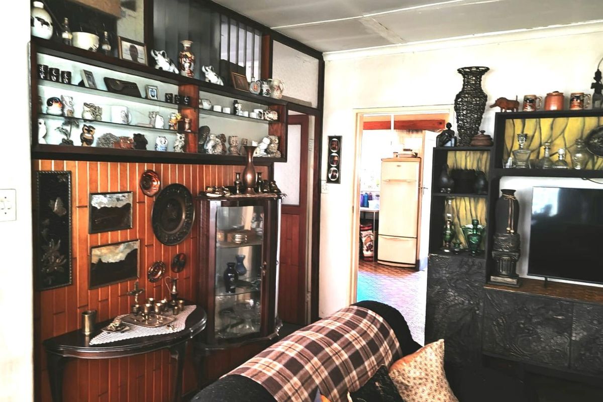 A living room featuring vintage wood paneling and built-in display cabinetry, with a view through to the adjacent kitchen area.