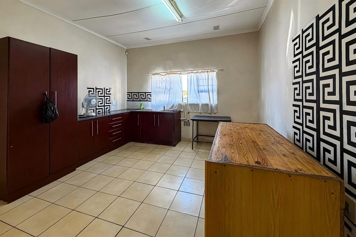 A functional kitchen area featuring dark wood cabinetry, tiled flooring, and a built-in sink unit with tiled splashbacks.