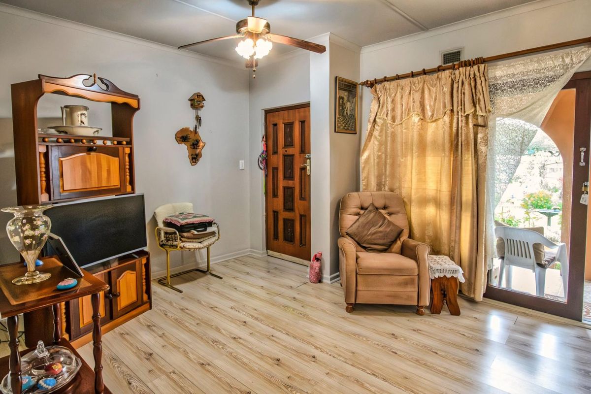 A living room featuring light wood-look laminate flooring, a ceiling fan, and a sliding glass door providing access to an outdoor patio area.
