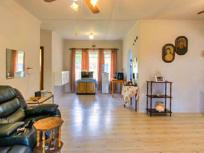Spacious open-plan living area featuring light-toned laminate flooring, ceiling fans, and large windows that provide natural light throughout the room.