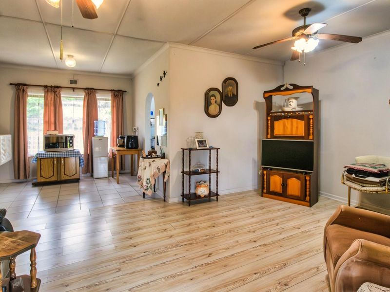 Open plan living area featuring a combination of tiled and wood-look laminate flooring, ceiling fans, and neutral wall finishes.