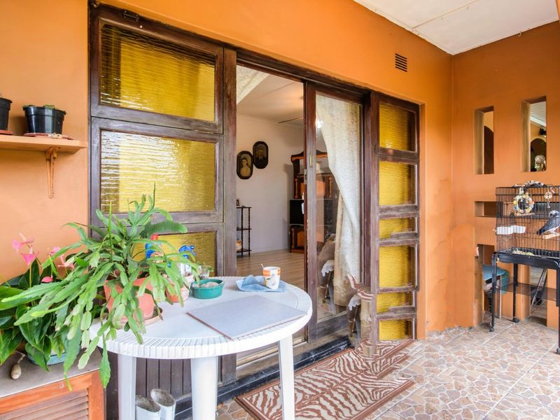 A covered patio area featuring tiled flooring and sliding glass doors providing access to the interior living space.