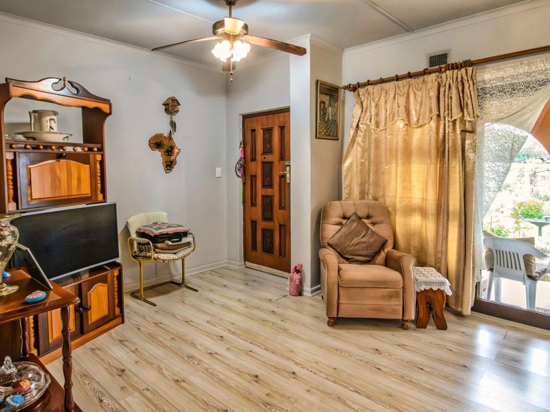 A living room featuring light wood-look laminate flooring, a ceiling fan, and a sliding glass door providing access to an outdoor patio area.