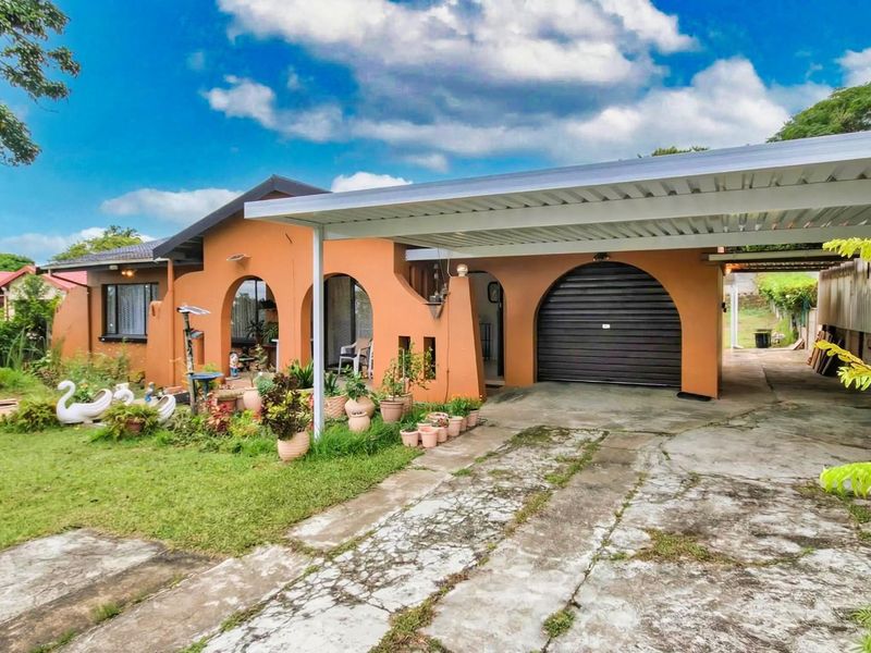 Front elevation of a single-story house featuring arched architectural details, a covered carport, and a front garden area.