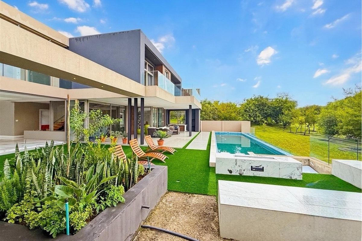 Modern rear exterior featuring a swimming pool, glass balustrades, covered patio, and landscaped garden area with built-in stone seating.