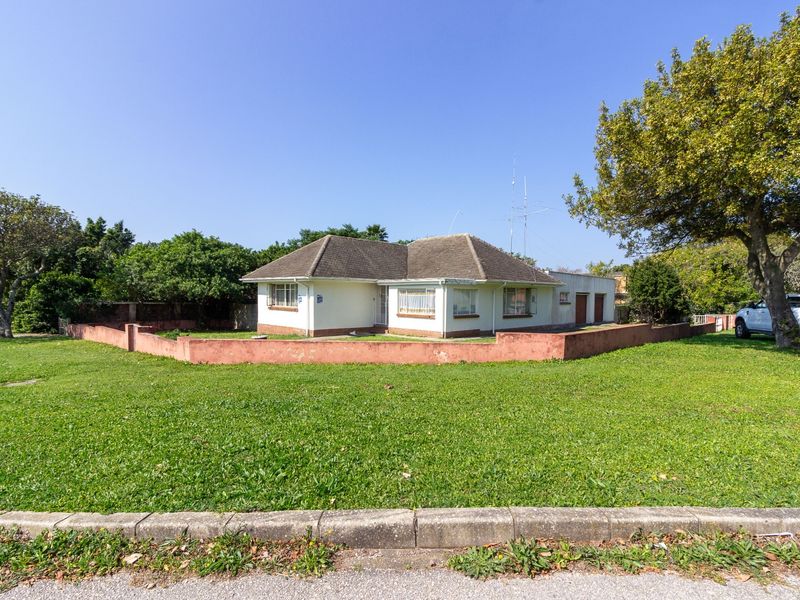 A detached single-story house featuring a tiled roof, perimeter wall, and attached garage, situated on a corner lot with a large front lawn.