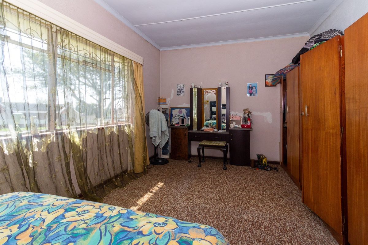 A bedroom featuring built-in wooden wardrobes and carpet flooring, requiring cosmetic updates to the wall finishes and flooring to improve its overall condition.