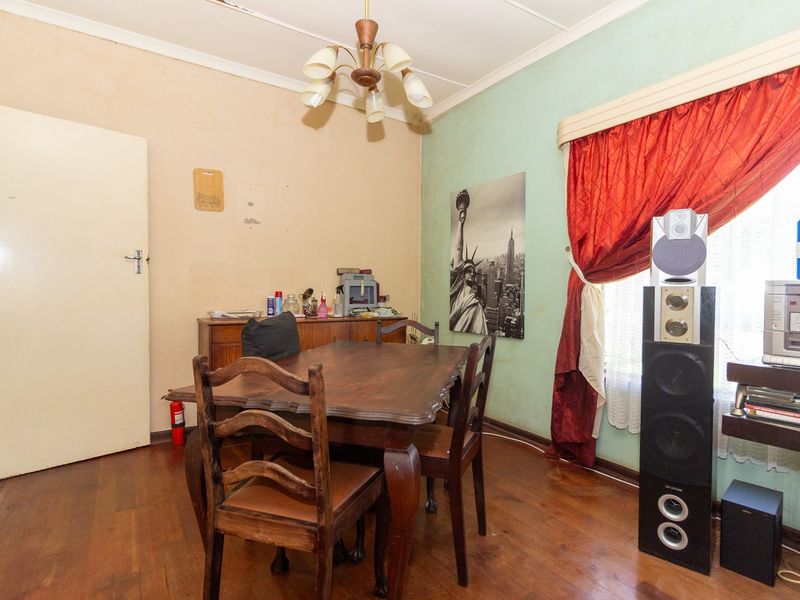 A dining room featuring hardwood flooring and a central light fixture, currently requiring cosmetic updates to the walls and ceiling.