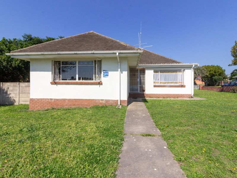 Front elevation of a single-story detached house featuring a tiled roof, brick plinth, and a concrete pathway leading to the entrance.