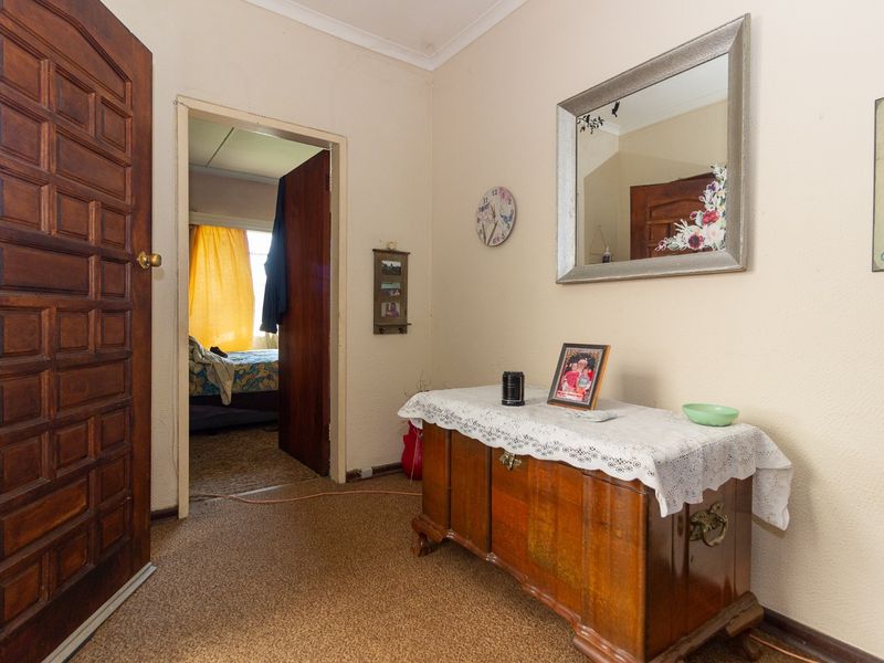 A functional hallway featuring carpeted flooring, coved ceilings, and a solid wood door, providing access to adjacent rooms.