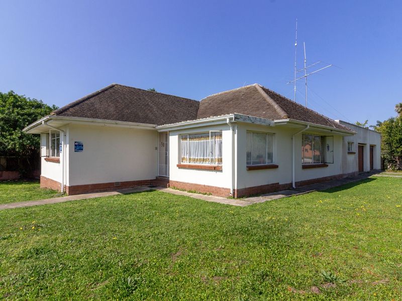 A single-story residential house featuring a tiled roof, plastered exterior walls with a brick base, and an attached garage, set on a grassed lot.