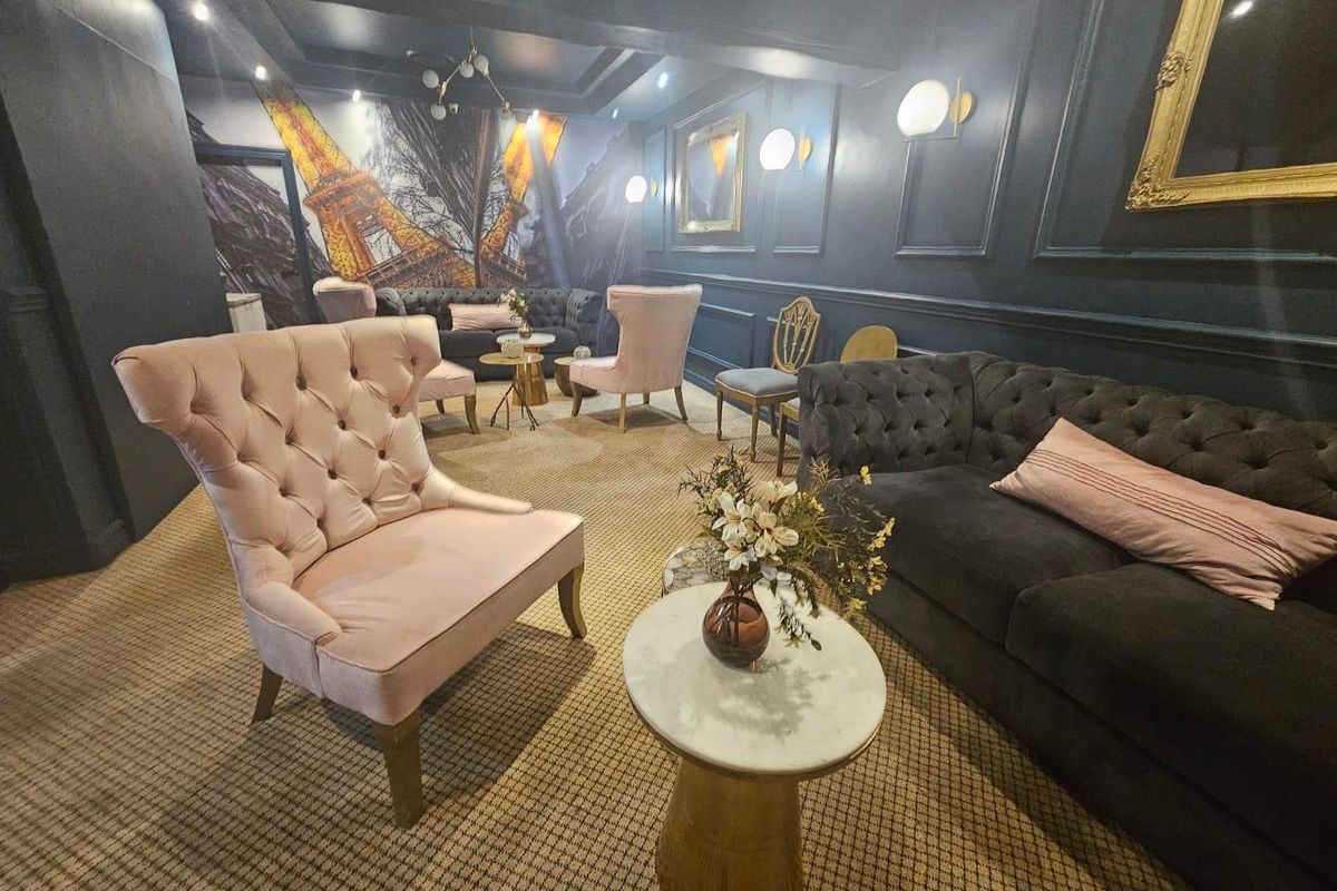 A sophisticated lounge area featuring dark paneled walls, decorative wall molding, and integrated wall lighting, creating an intimate and elegant atmosphere.