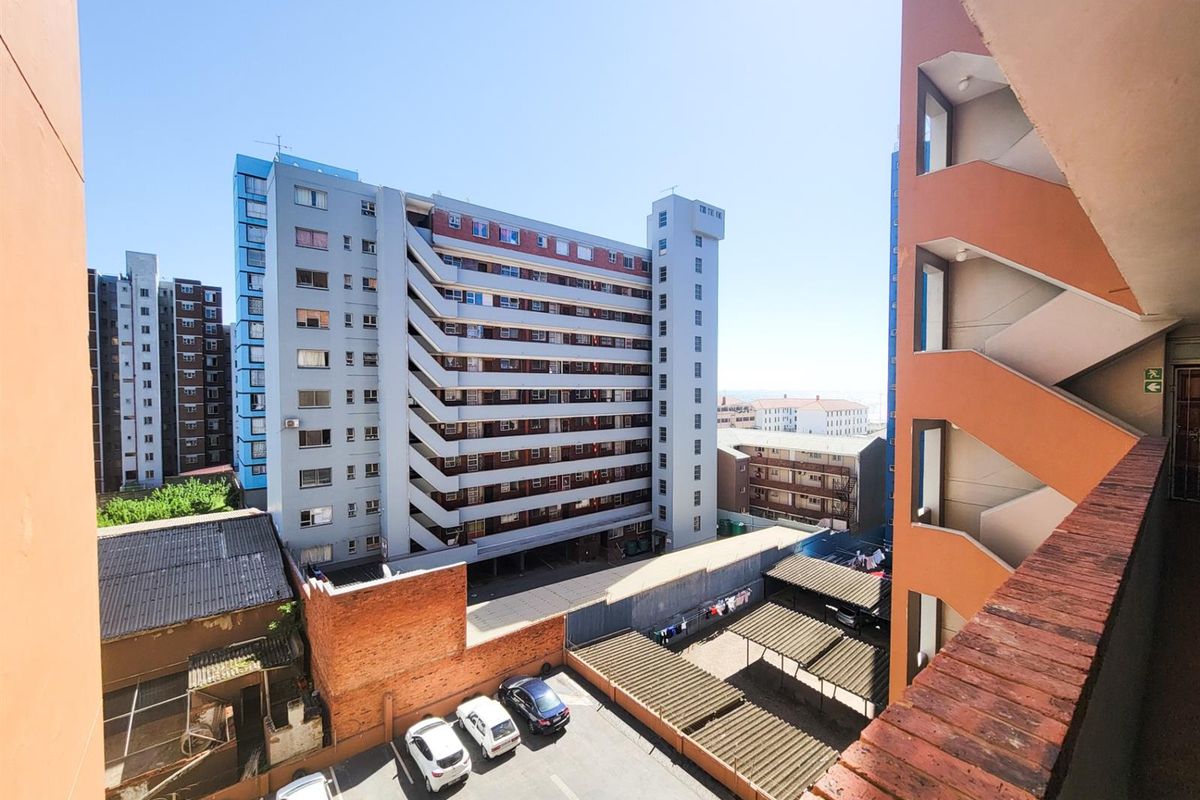 View from an apartment balcony overlooking the building's rear parking area, stairwell, and surrounding residential complex.