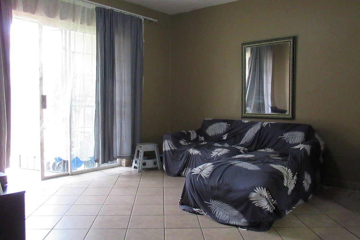 A living room featuring tiled flooring and a large sliding glass door providing access to an outdoor area.
