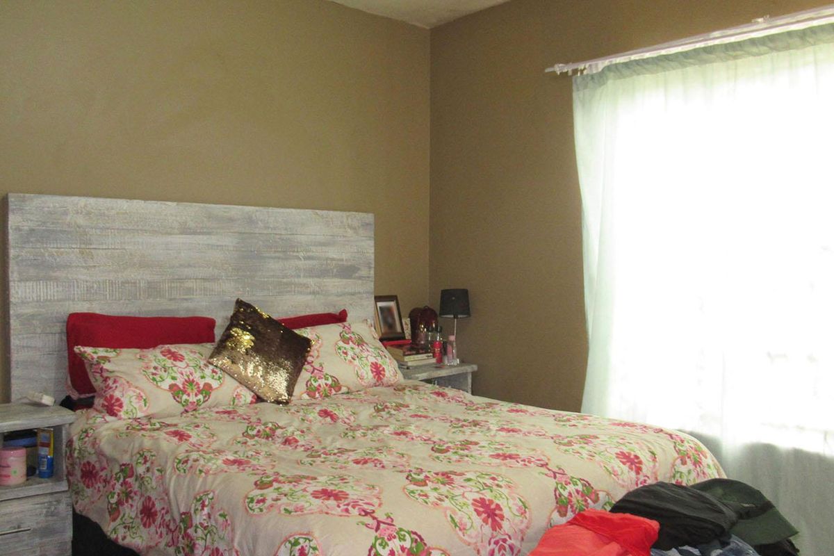 A bedroom featuring neutral wall tones and a window with sheer curtains, providing natural light to the space.