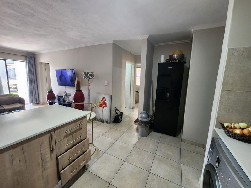 Open plan living area featuring a kitchen island with wood-finish cabinetry, tiled flooring, and seamless flow into the adjacent living space.