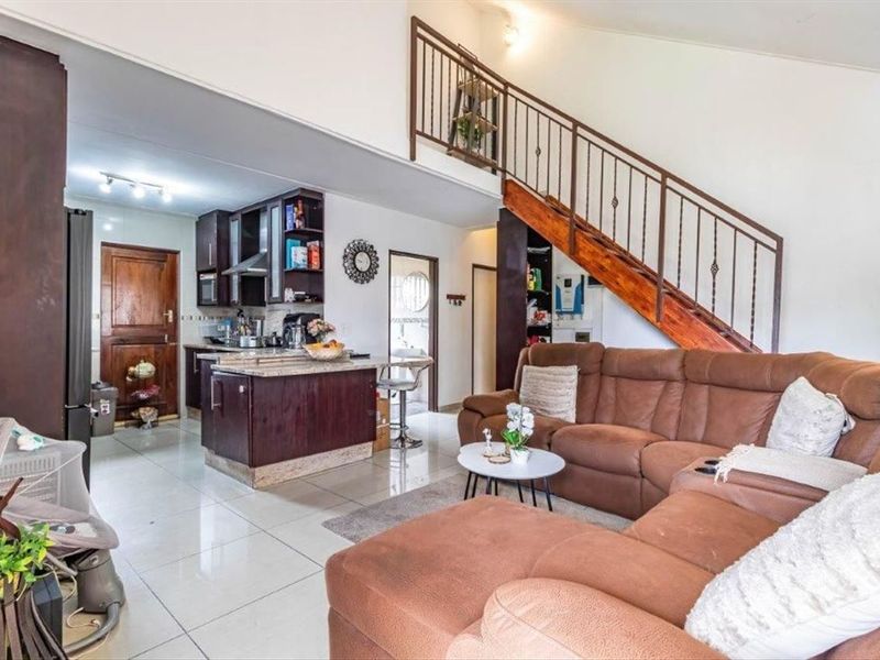 Open plan living area featuring a kitchen with dark wood cabinetry, tiled flooring, and a staircase leading to an upper level.