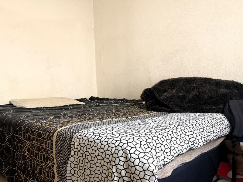 A simple bedroom space featuring plain walls and standard electrical fixtures, providing a functional area for rest.