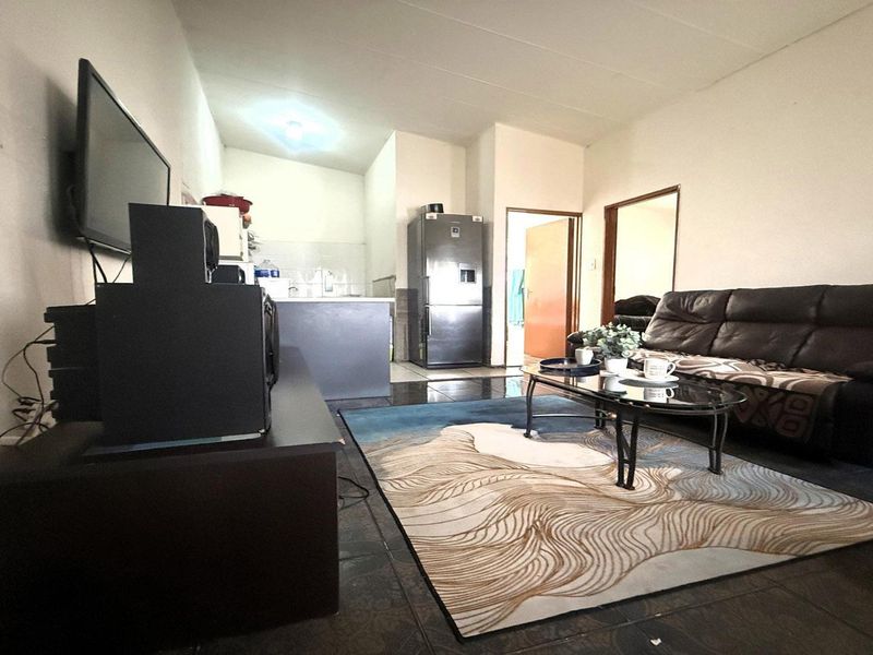 Open-plan living area featuring tiled flooring and a compact kitchen space, providing a functional layout for daily living.