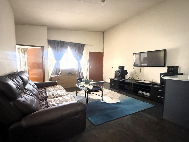 A functional living room area featuring tiled flooring and neutral wall finishes, providing a versatile space for relaxation.