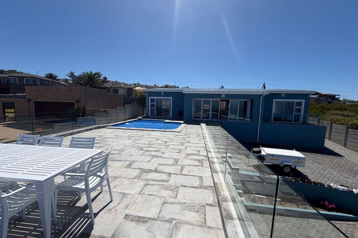 Spacious rear patio area featuring a swimming pool with cover, glass balustrades, and paved outdoor entertainment space overlooking the property.