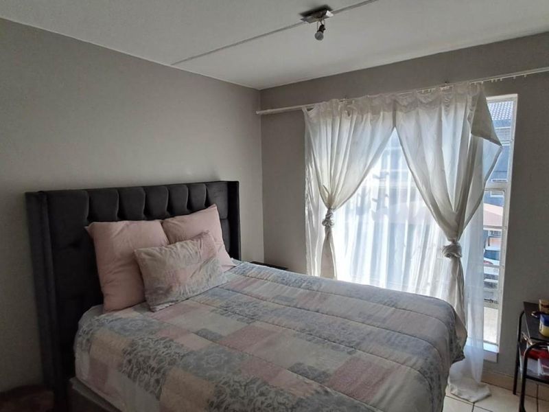 A functional bedroom featuring neutral wall tones and natural light through a window with a fitted curtain rail.