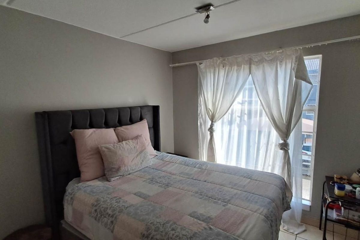 A functional bedroom featuring neutral wall tones and natural light through a window with a fitted curtain rail.