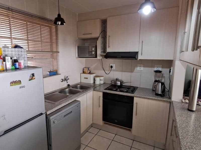 Compact kitchen featuring laminate cabinetry, granite-look countertops, a double bowl sink, built-in oven, gas hob, and tiled finishes throughout.