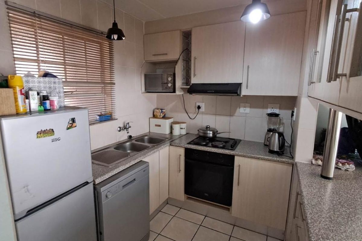 Compact kitchen featuring laminate cabinetry, granite-look countertops, a double bowl sink, built-in oven, gas hob, and tiled finishes throughout.