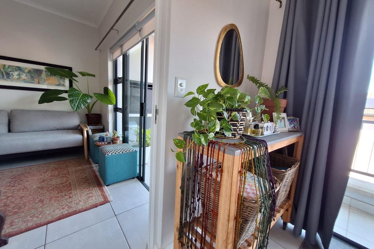 A bright living area featuring tiled flooring and a sliding glass door that provides access to an outdoor balcony space.