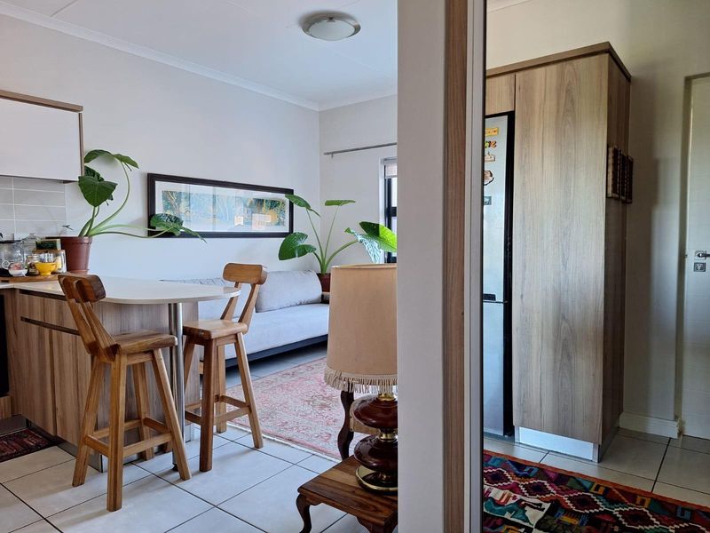 An open-plan living and kitchen area featuring tiled flooring, built-in cabinetry, and a functional breakfast bar layout.
