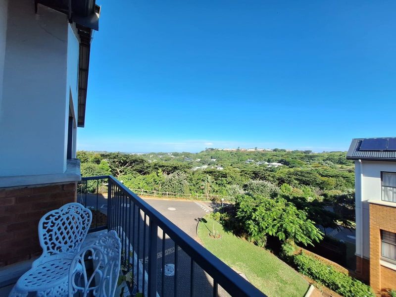 A balcony featuring a metal balustrade with expansive views over the surrounding landscape and residential area.