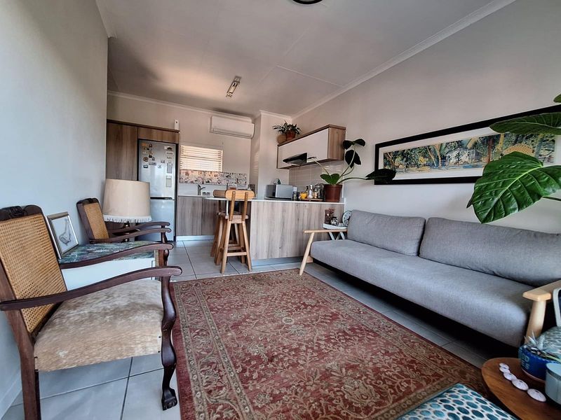 Open-plan living area featuring a functional kitchen with built-in cabinetry, tiled flooring, and an integrated air conditioning unit.