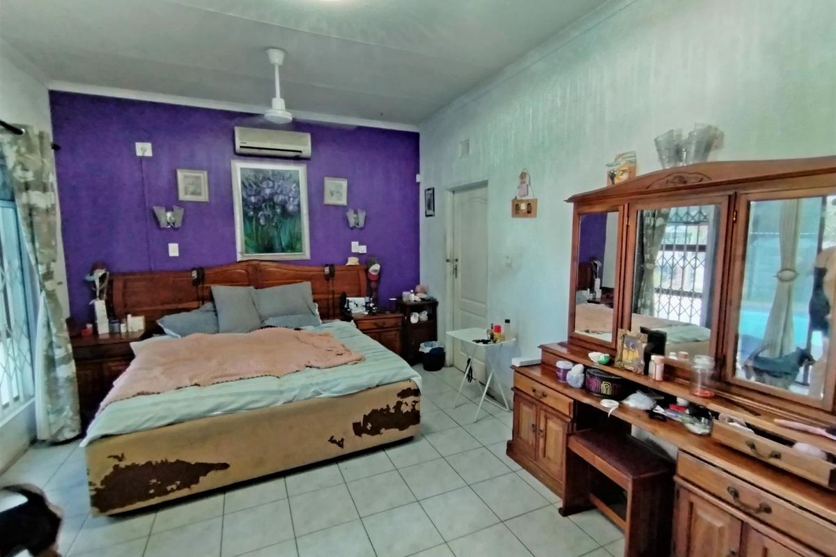 Spacious bedroom featuring tiled flooring, a ceiling fan, and a wall-mounted air conditioning unit.