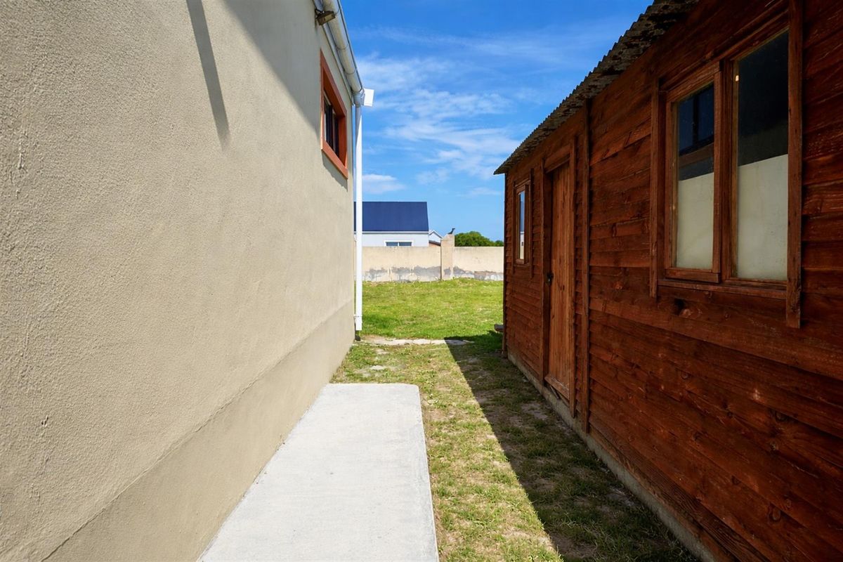 Side passage between the main dwelling and a timber outbuilding, featuring a concrete walkway and access to the rear garden area.