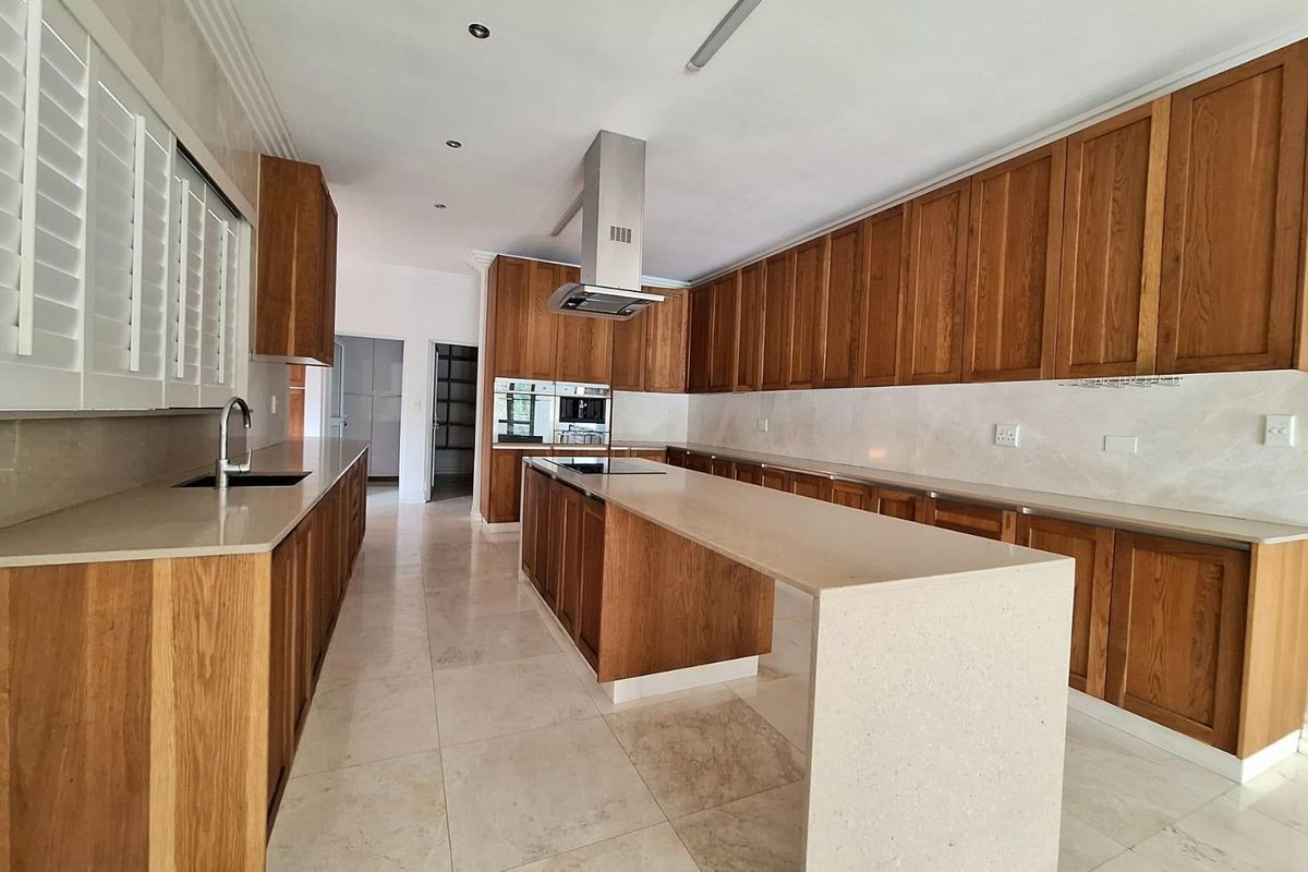 Spacious kitchen featuring extensive wooden cabinetry, stone countertops, a central island with breakfast bar, and integrated stainless steel appliances.