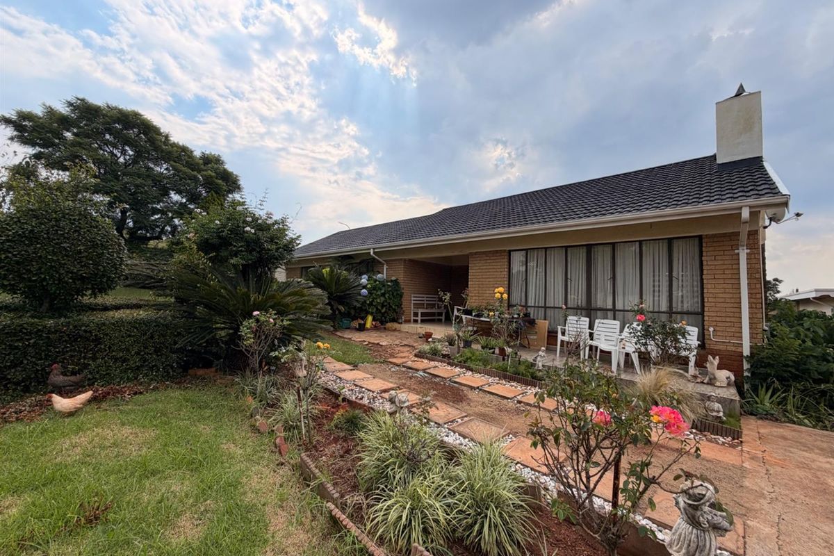 A view of the rear exterior of the house featuring a brick facade, tiled roof, and a landscaped garden with a paved walkway.