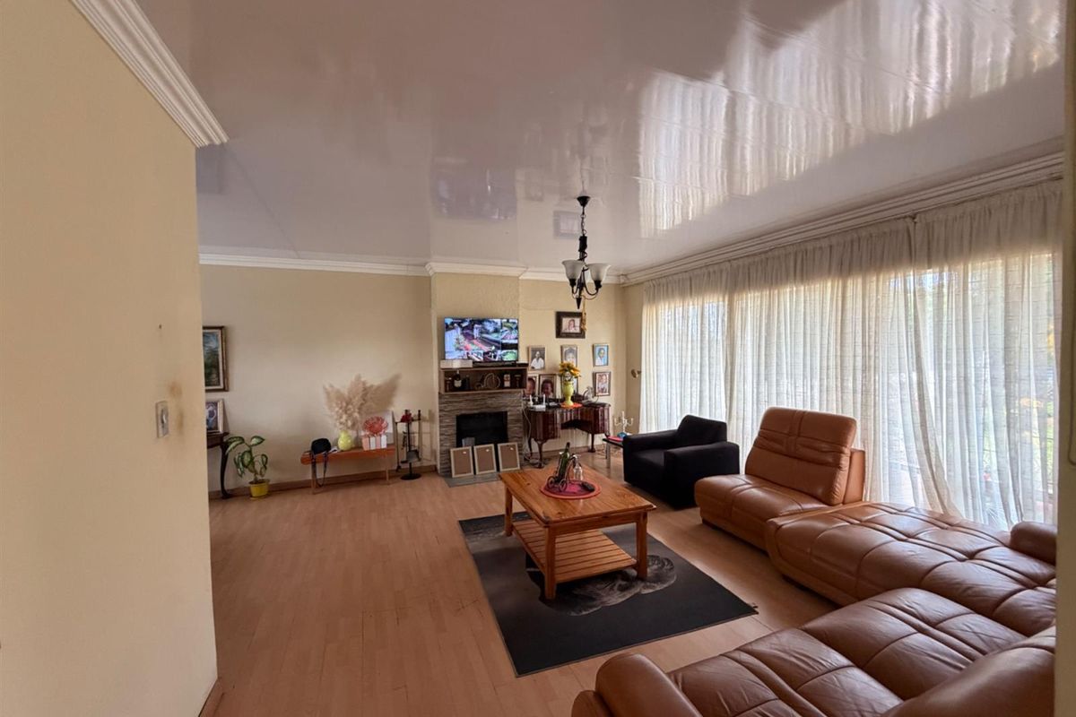 Spacious living room featuring a built-in fireplace, high-gloss ceiling finish, and large windows with floor-to-ceiling curtains allowing for ample natural light.